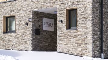 Ein Gebäude mit einer Steinauffahrt, einem Schild mit der Aufschrift 'Moose Lodge Happy Holidays' und einem mit Schnee bedeckten Gelände.