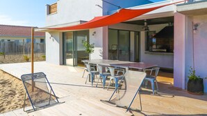 Een modern terras buiten, met een houten terras, metalen stoelen en een tafel.