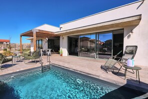 A modern outdoor pool area with lounge chairs and a pergola.