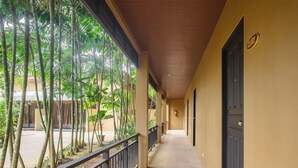 A corridor with a wooden ceiling, a metal railing, and a view of tropical plants. - Naiyang Beach Hotel (Sa Khu)
