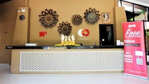 A reception desk with decorative sunflowers, a clock, and a sign offering a 100% discount voucher. - Naiyang Beach Hotel (Sa Khu)