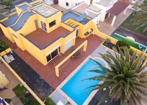 Ein gelbes Gebäude mit Schwimmbad und Terrassenbereich.