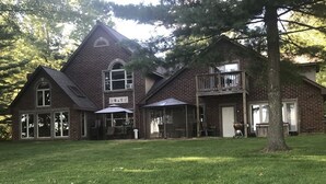 A large brick house with a covered patio area, a front porch, and a two-story balcony.