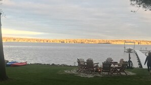 A lakeside outdoor seating area with Adirondack chairs and a fire pit.