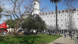 A historic building with a clock tower, surrounded by trees and a paved walkway. - Dom Luis I Prestige Flat 18 (Lisboa)
