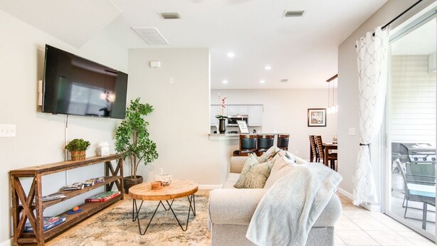 A modern living room with a sofa, a coffee table, a TV, and a bookshelf. - Serene - Fully Furnished Immaculate with 2-car Garage! (Lutz)