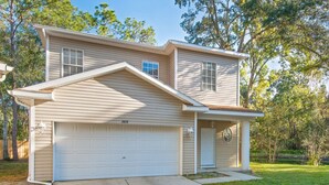 A two-story house with a garage, a covered porch, and a well-maintained lawn. - Serene - Fully Furnished Immaculate with 2-car Garage! (Lutz)