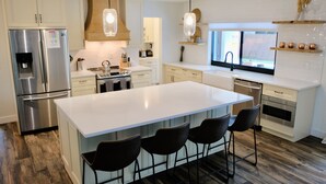 Una cocina moderna con una isla grande, electrodomésticos de acero inoxidable y vistas al exterior.