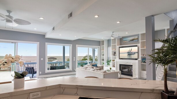 Un amplio salón con chimenea, ventanas grandes y vista al océano.
