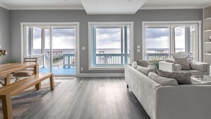 Un salón amplio con un ventanal grande que da a una terraza y al océano.