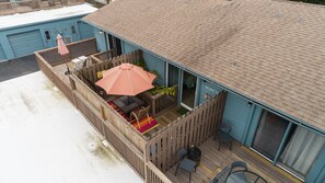 A blue building with a covered patio area featuring a table, chairs, and an umbrella.