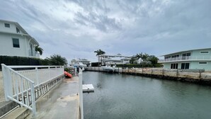 Un puerto deportivo con barcos amarrados, un edificio blanco con balcón y un cielo nublado.