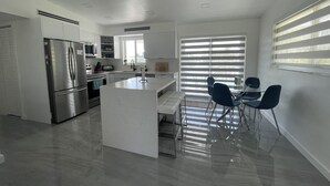 Una cocina moderna con una isla central, electrodomésticos de acero inoxidable y un comedor con sillas.
