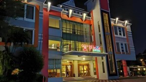 A multi-story hotel with a prominent neon sign, large windows, and a balcony on the second floor.