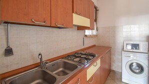 Eine Küche mit Holzausbau, einem Gasherd, Edelstahlspülen und einer Waschmaschine.