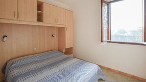Ein Schlafzimmer mit Bett, Holzschrank und Fenster mit Blick.