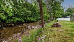 A serene outdoor setting with a stream, lush greenery, and a wooden structure. - Cabin by the Creek with private creek access - (Tannersville)