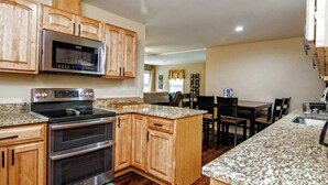A kitchen with wooden cabinets, a microwave, a stove, and granite countertops. - Cabin by the Creek with private creek access - (Tannersville)
