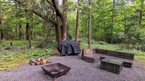 Un terrain de camping équipé d'un foyer, d'un espace détente et d'un barbecue couvert.