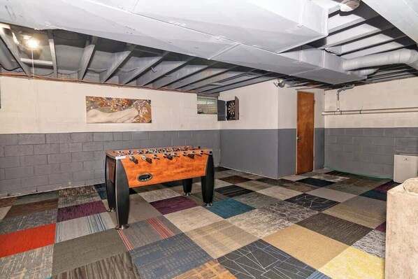 A room with a foosball table, a patterned carpet, and a door.
