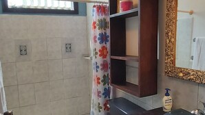 Een badkamer met douche, toilet en wastafel.