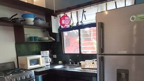 Een praktische keuken met een gasfornuis, een magnetron en een roestvrijstalen koelkast.