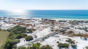 Vista aérea de una zona costera con playa de arena, un paseo marítimo de madera y un cartel que dice 'SoWa'.