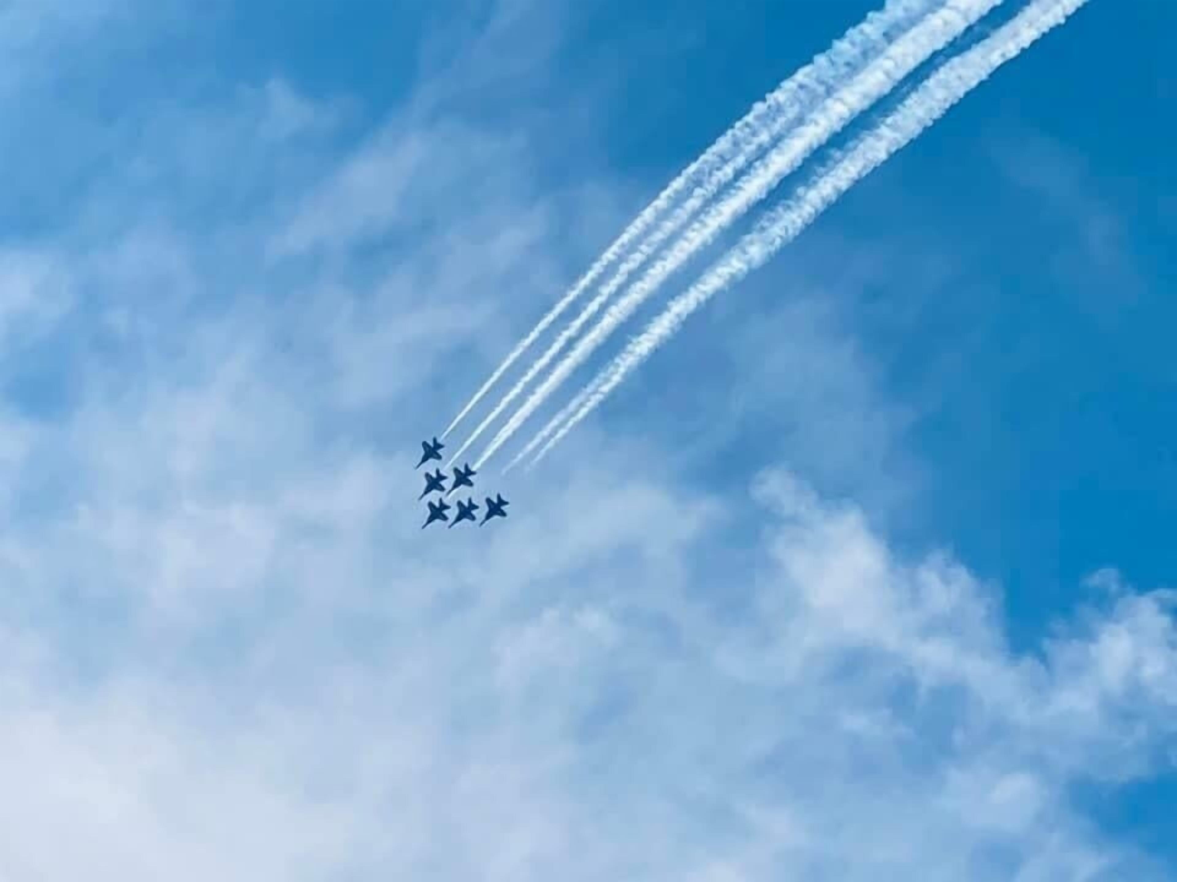 A clear blue sky with a formation of jets leaving contrails.