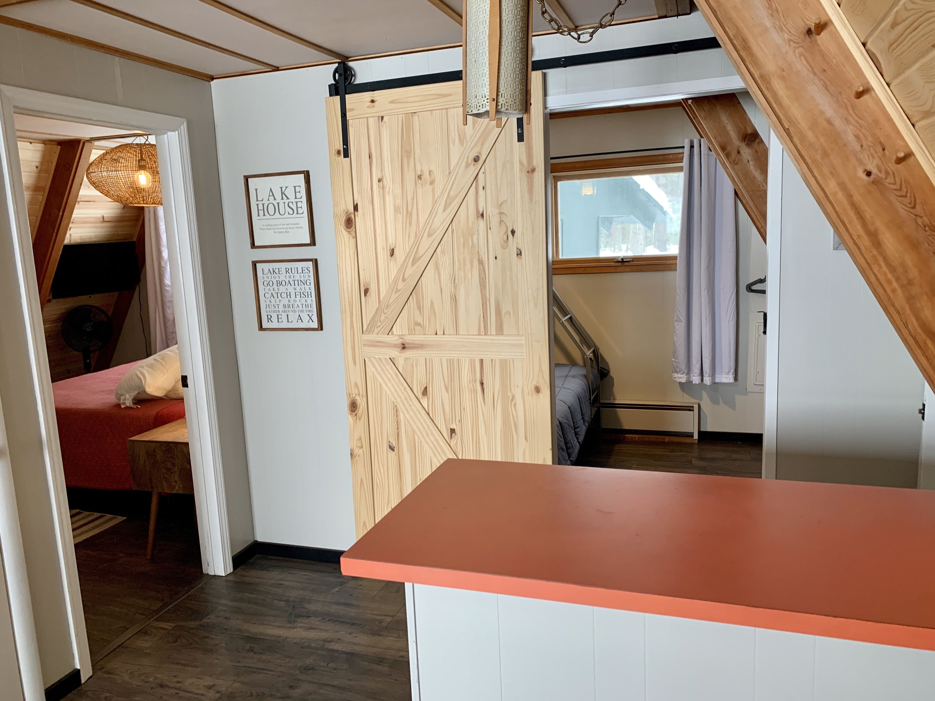 Ein Zimmer mit Holztür, einem Bett, einem roten Sofa und einem kleinen Tisch.
