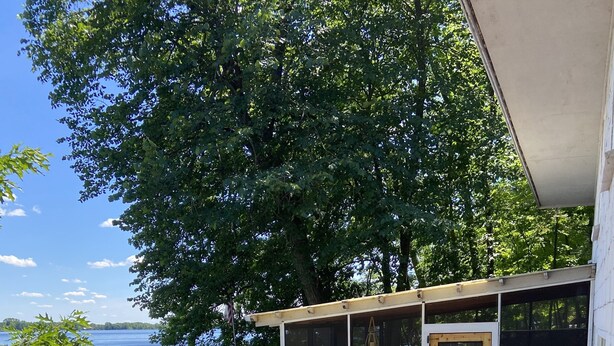 A deck with outdoor seating, a view of the lake, and a covered area with large windows. - Top-Rated Balsam Lake Vacation Home with Stunning Lake Views, 4 BR & Family Fun (Balsam Lake)