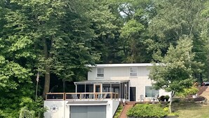 A house with a dock extending into a lake, surrounded by dense trees. - Top-Rated Balsam Lake Vacation Home with Stunning Lake Views, 4 BR & Family Fun (Balsam Lake)