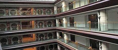 A multi-level atrium with glass railings and a geometric ceiling design.
