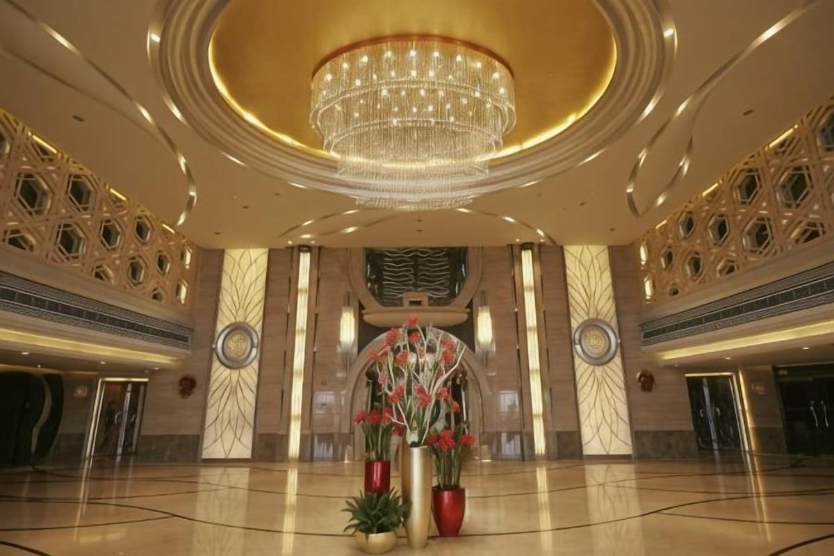 A spacious lobby with a large chandelier, decorative columns, and potted plants.