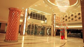 A spacious lobby with a large, geometric pillar, a grand chandelier, and a modern reception desk. - Dazhong Airport Hotel (Shanghai)