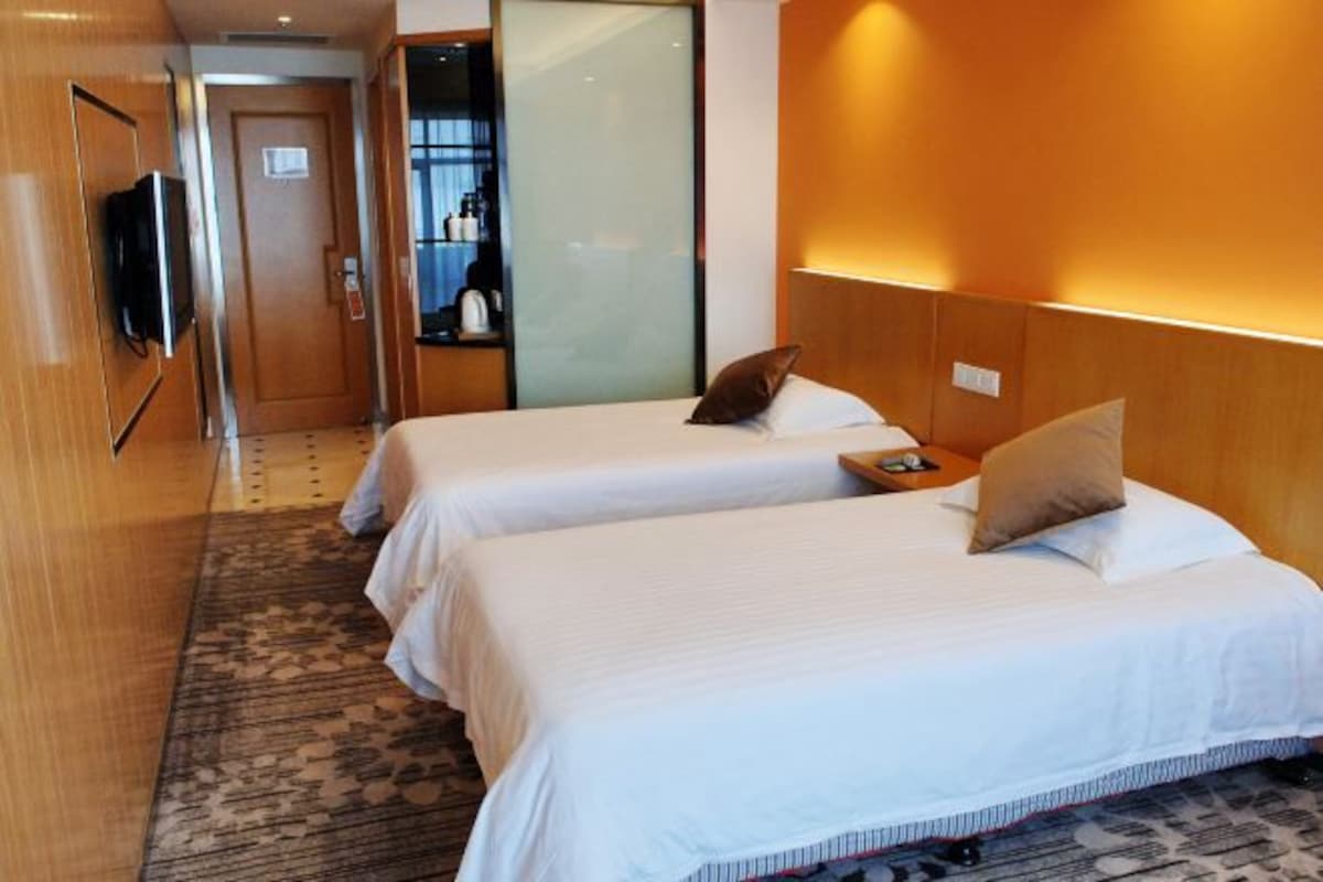 A hotel room with two beds, a television, and a minibar.