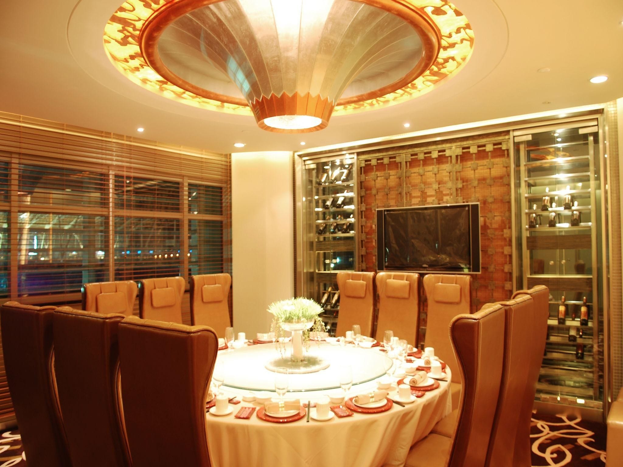 A dining area with a round table set for a meal, surrounded by leather chairs.