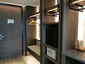 A hotel room with a wardrobe, a hanging coat rack, a built-in safe, and a small seating area. - Dazhong Airport Hotel (Shanghai)