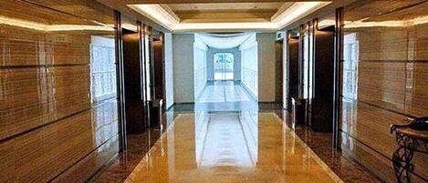 A long, polished corridor with a reflective floor and wooden paneling on the walls.