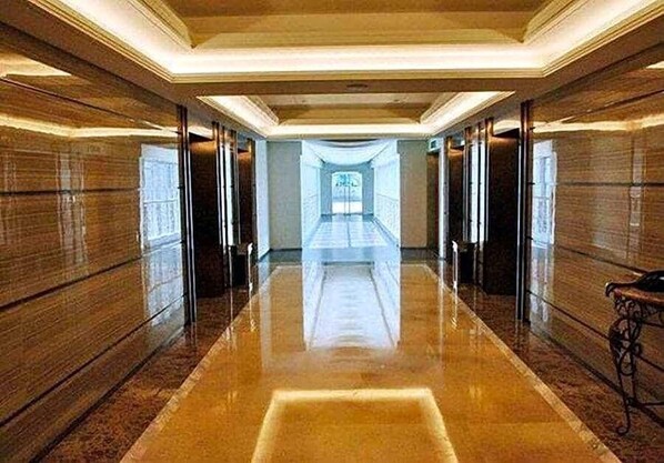 A long, polished corridor with a reflective floor and wooden paneling on the walls.