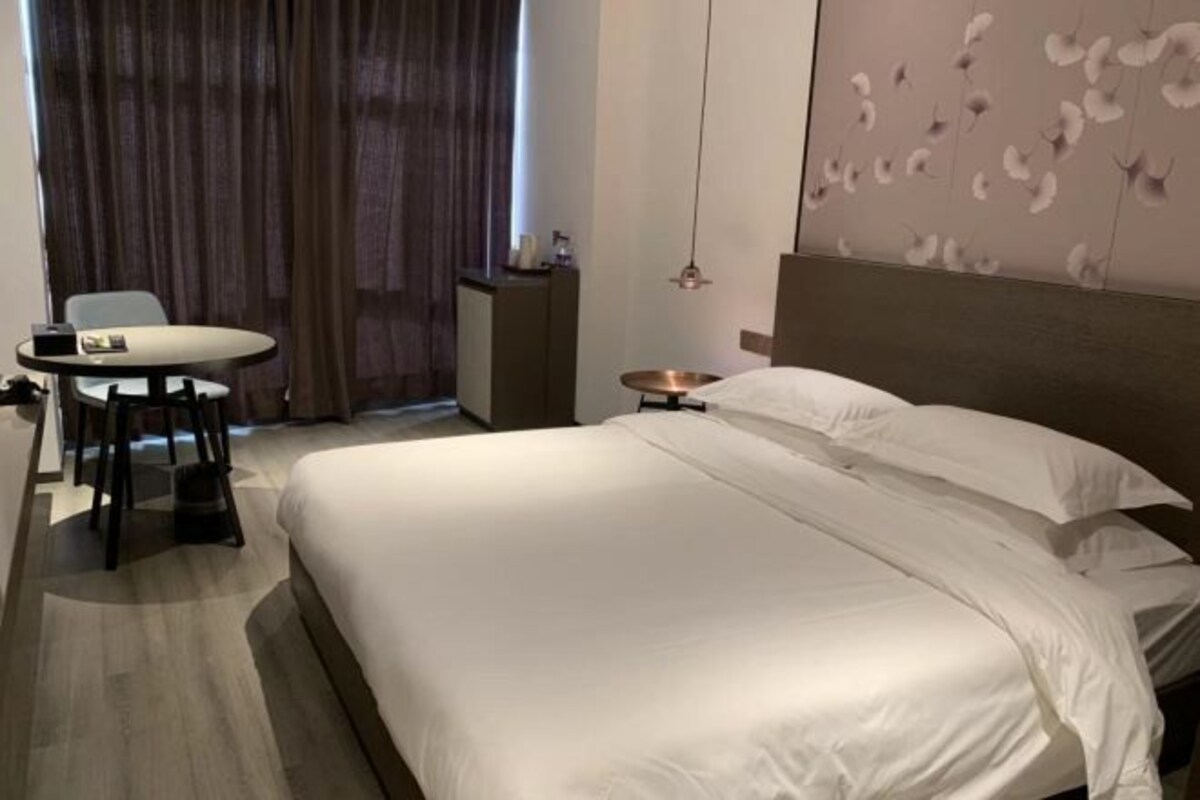 Una habitación de hotel con una cama grande, una mesa redonda pequeña y una silla.