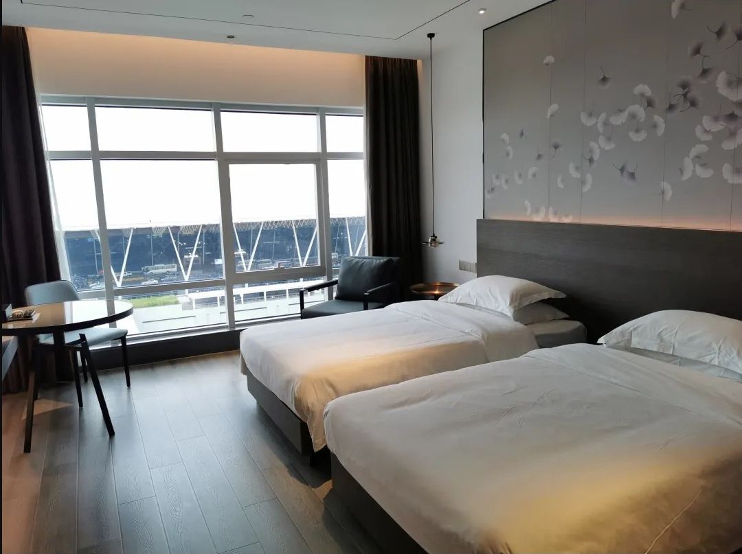 Une chambre d’hôtel avec deux lits, un bureau et une grande fenêtre donnant sur un pont.