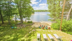A lakeside outdoor seating area with chairs and a fire pit.