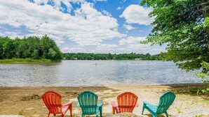 A lakeside view with four Adirondack chairs facing the water.