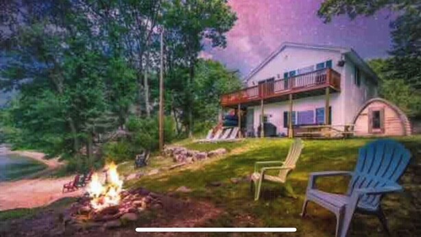 A house with a porch, a fire pit, and two chairs.
