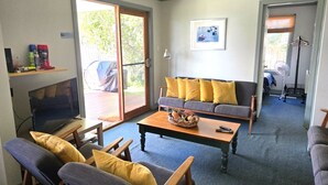 A living room with a sofa, chairs, a coffee table, and a television. - Fishermans Cottage - Queenscliff (QUEENSCLIFF)