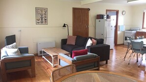 A cozy living room with a sofa, two armchairs, a coffee table, and a dining area with a table and chairs. - The Beach Shack - Queenscliff (Queenscliff)