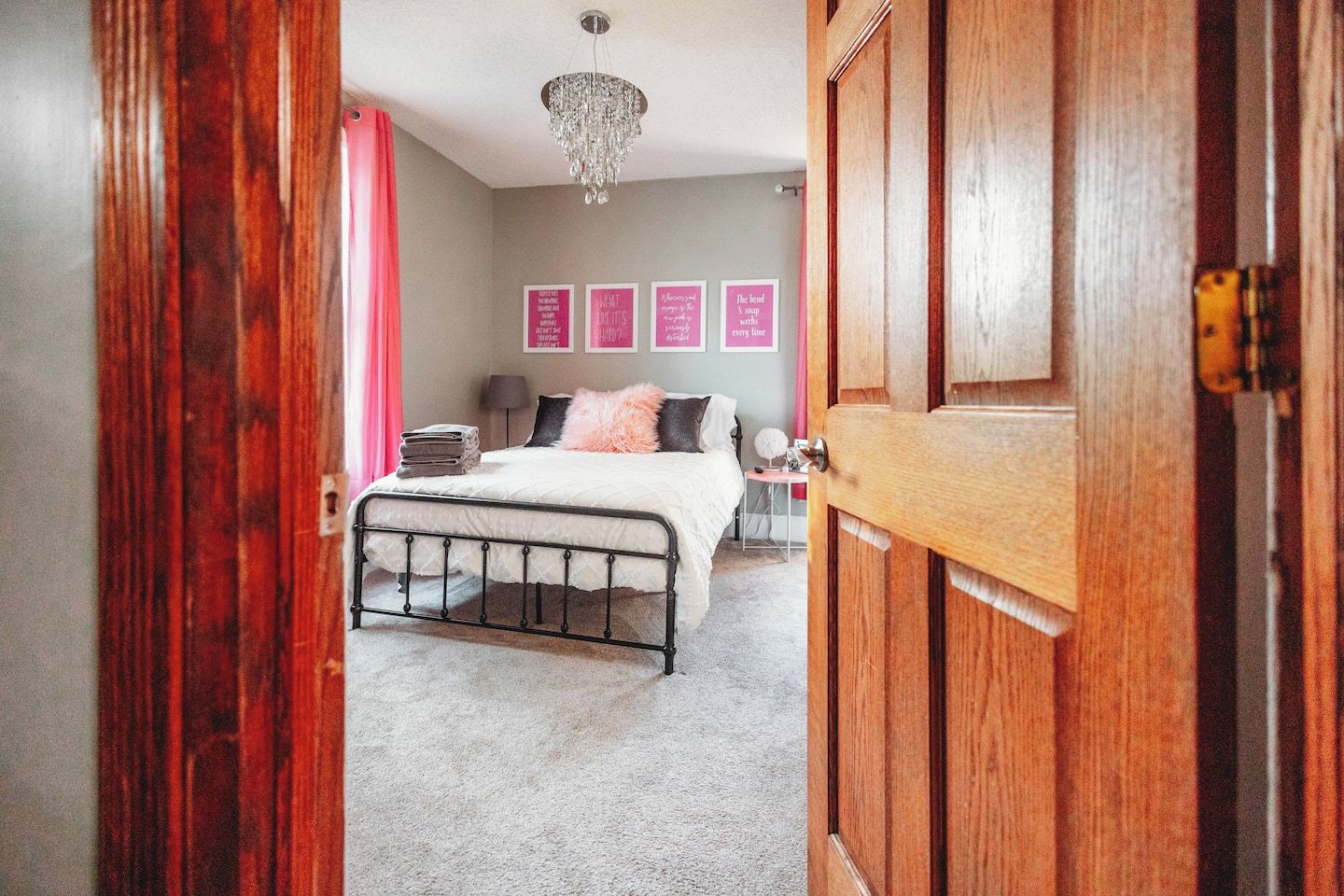 A bedroom with a bed, a chandelier, and a door.