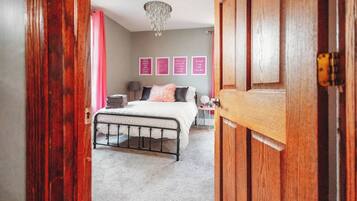 A bedroom with a bed, a chandelier, and a door.