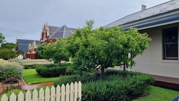 A residential area with a well-maintained garden, a white picket fence, and a house with a modern roof.