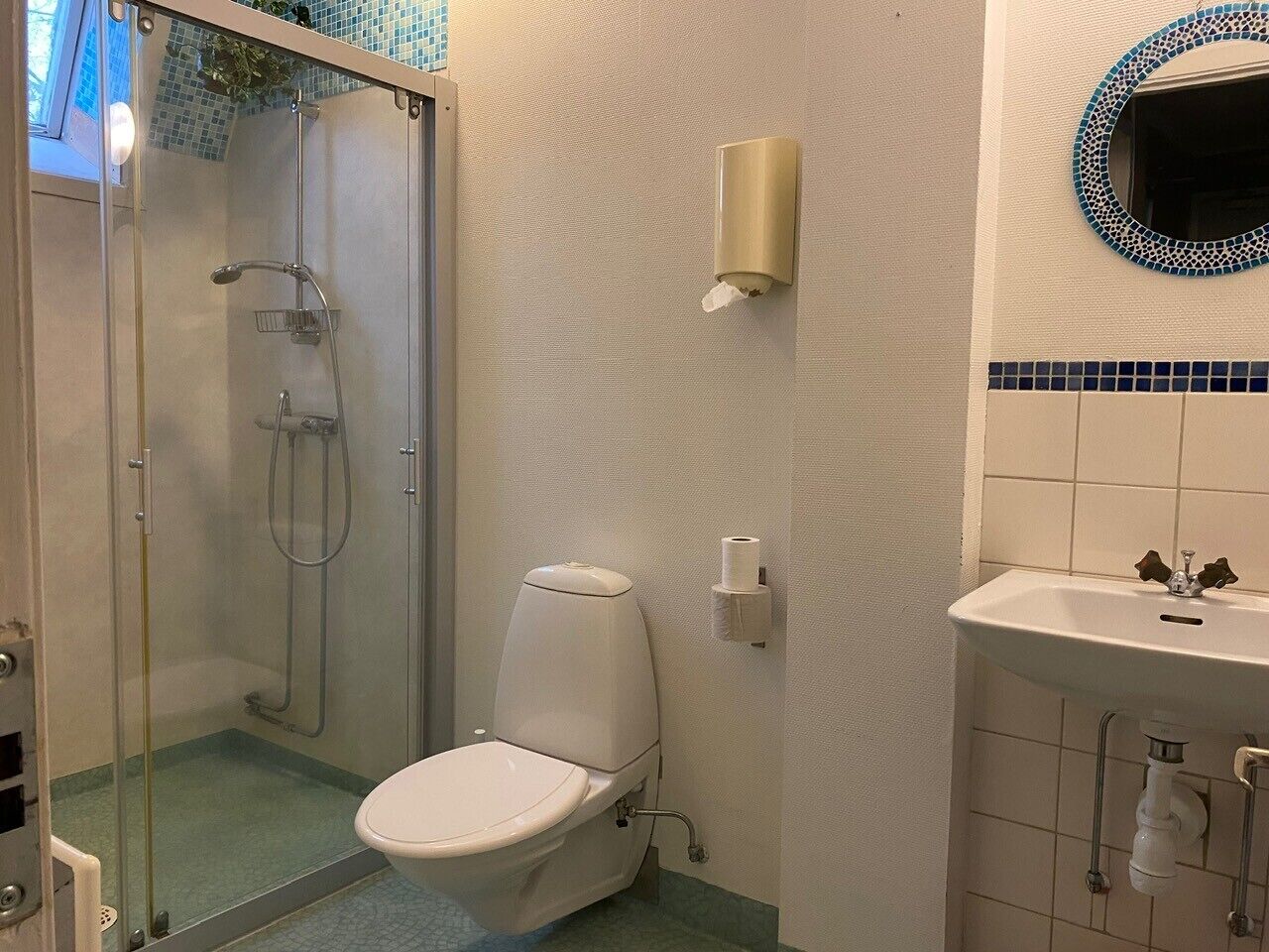 Une salle de bain avec une douche à parois de verre, des toilettes, un lavabo et un miroir fixé au mur.